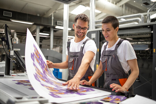 Two print professionals reviewing large-format purple graphics at a production facility
